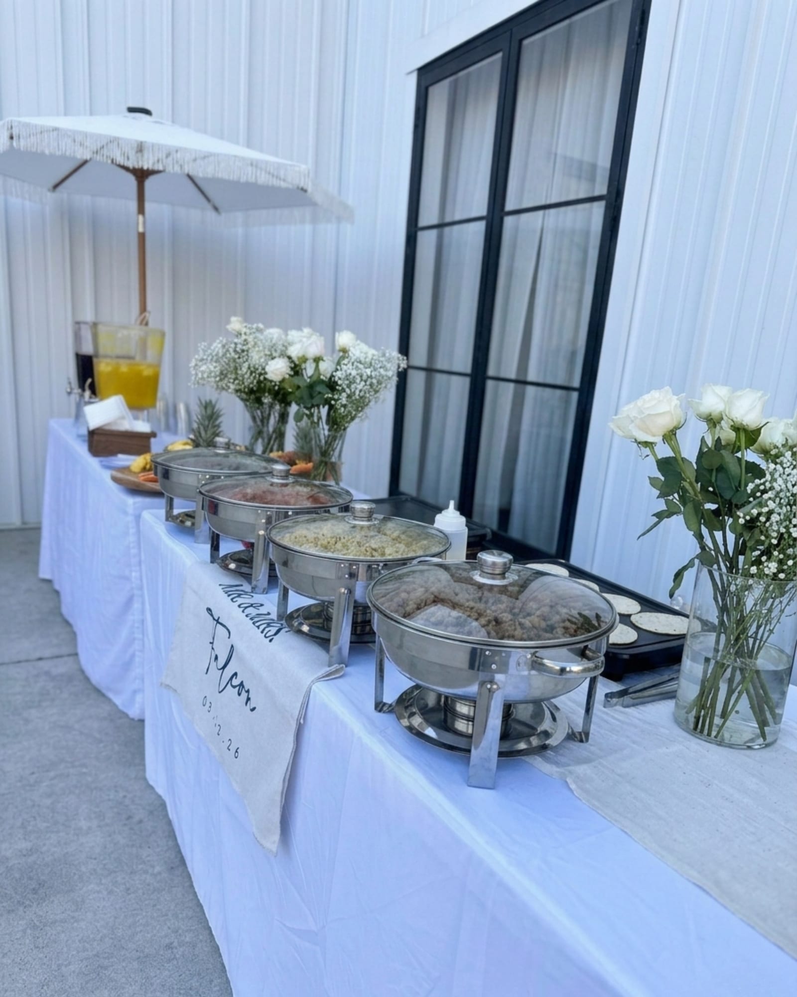 Outdoor buffet with white linens, chafing dishes and fresh flowers