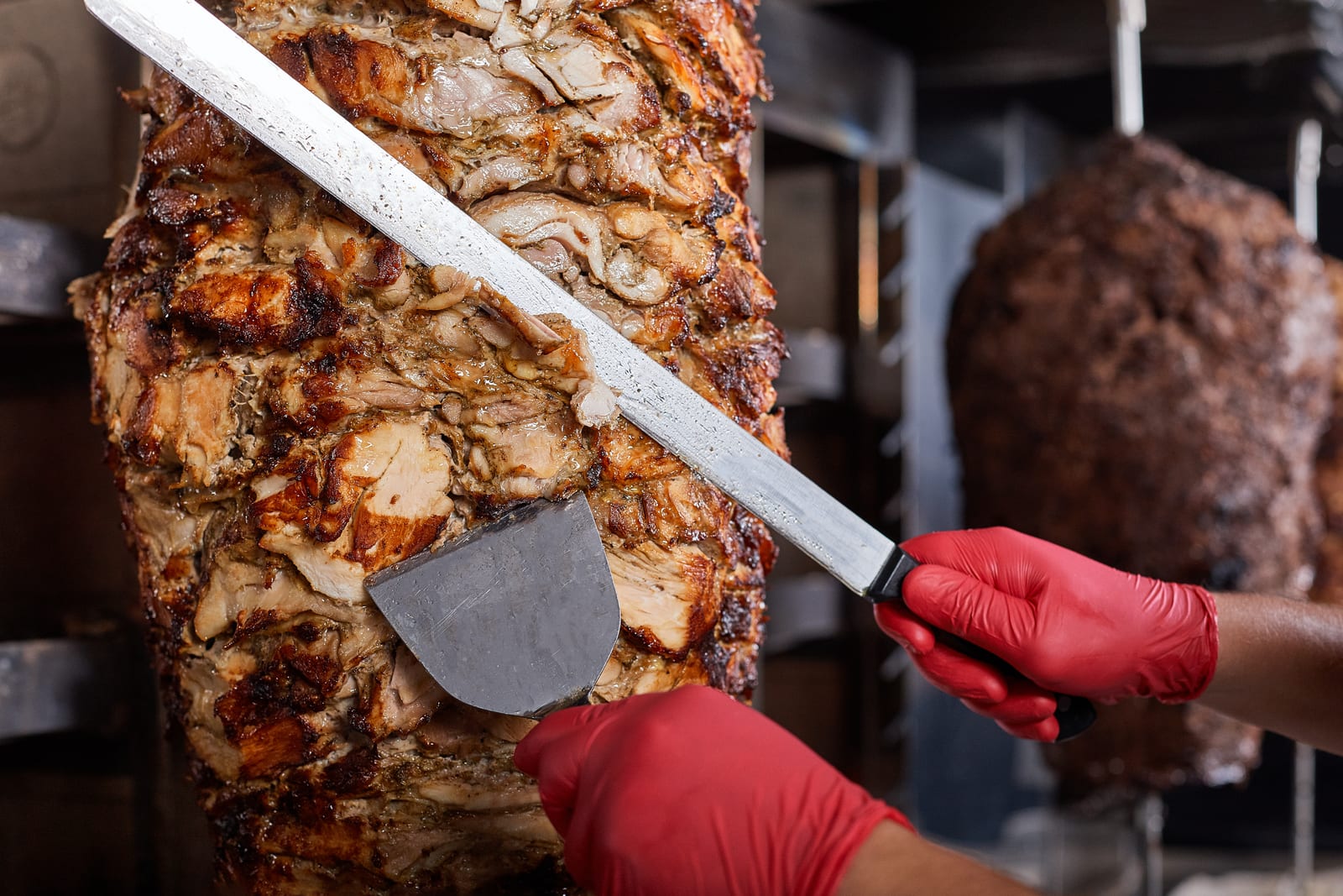 Al pastor pork being sliced from the spit