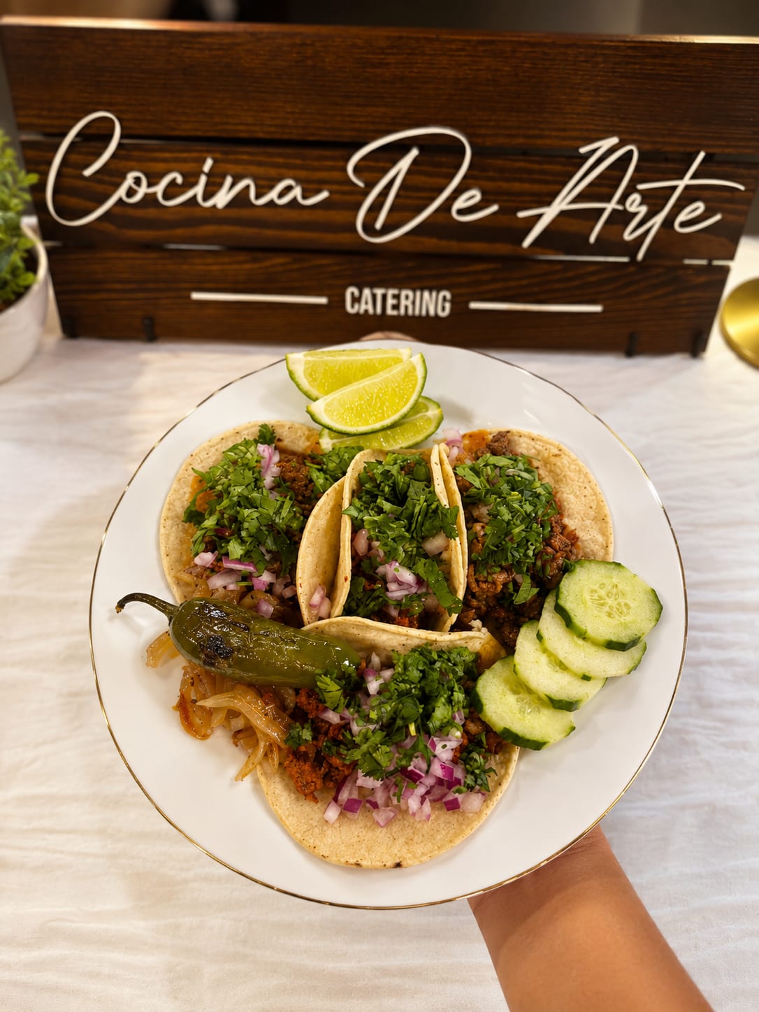Plate of tacos with limes in front of the Cocina de Arte Catering sign